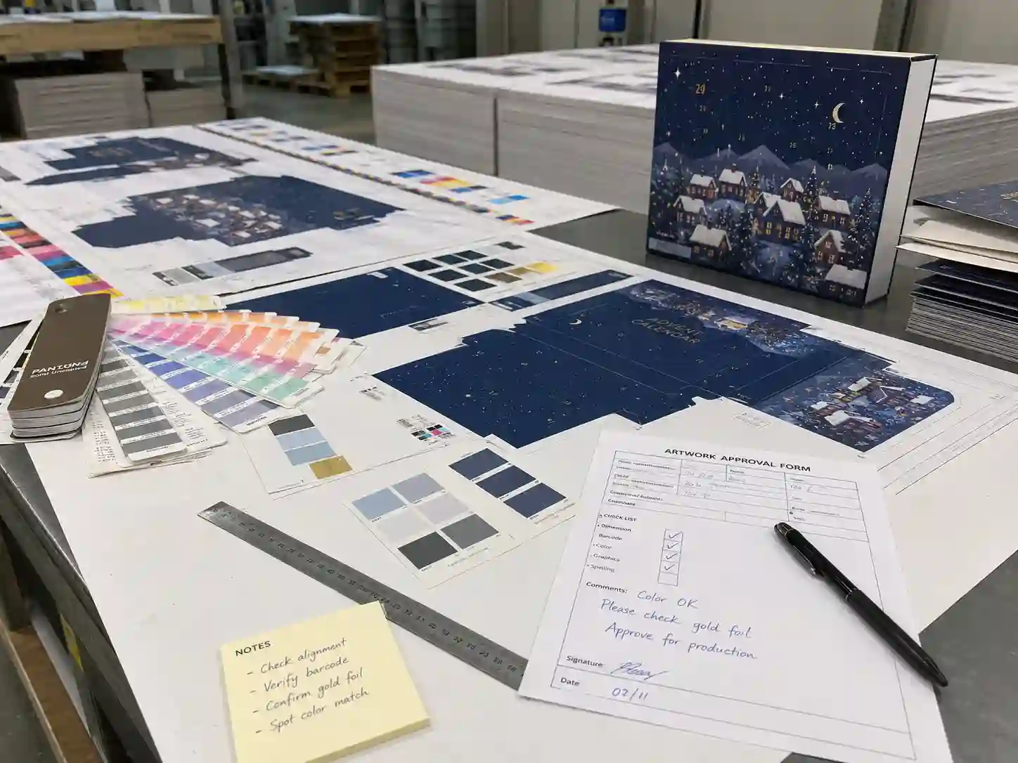 Printing proof table with Pantone cards and CMYK sheets for advent calendar box artwork approval