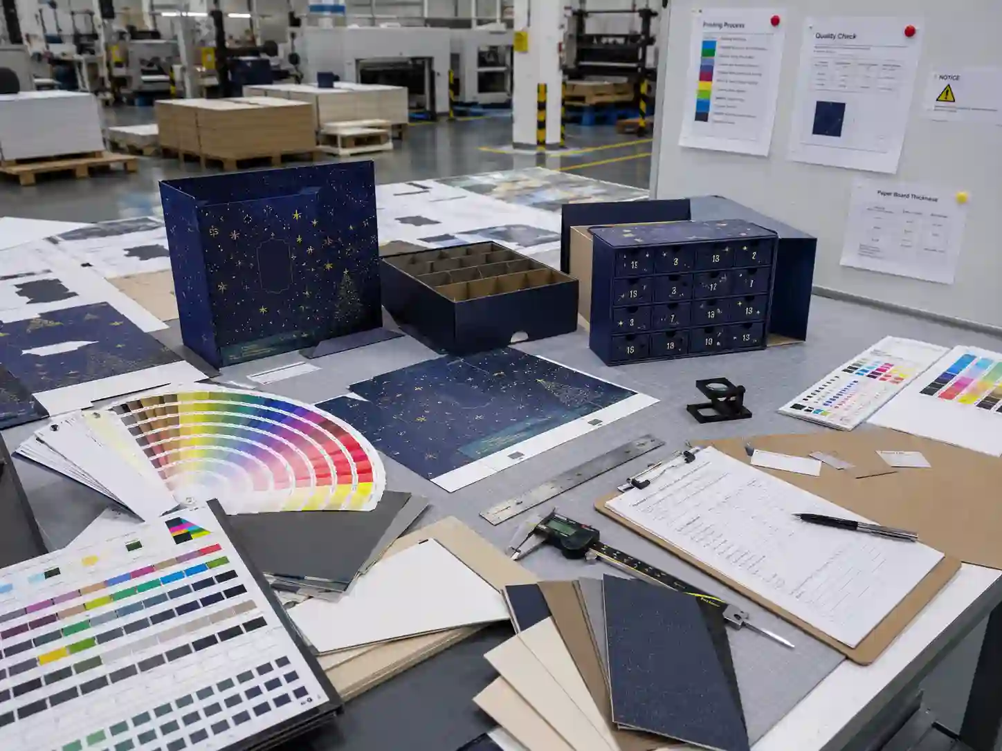 Printing proof table with Pantone cards and CMYK sheets for drawer advent calendar box artwork review