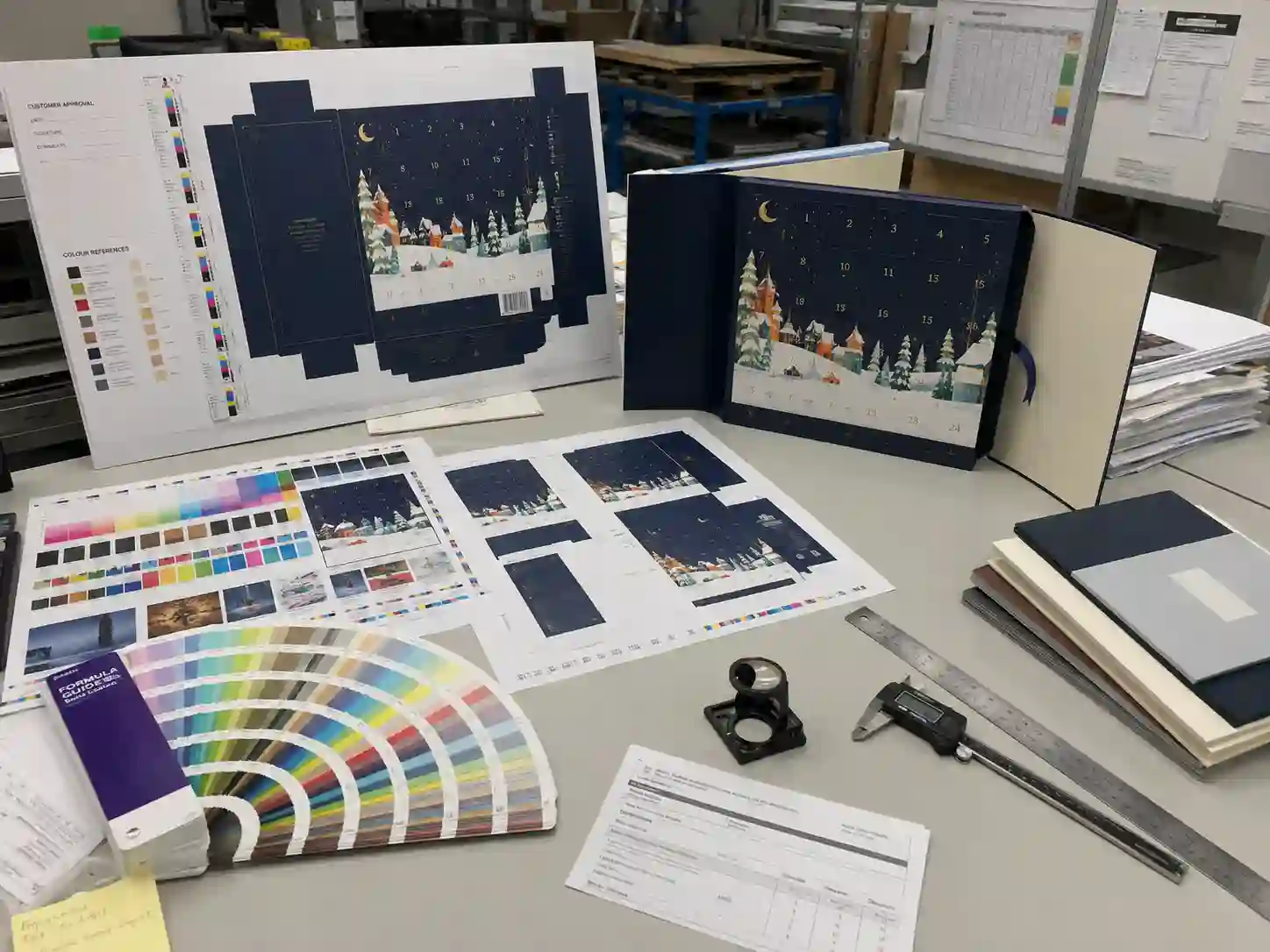Printing proof table with Pantone cards and CMYK sheets for rigid advent calendar boxes