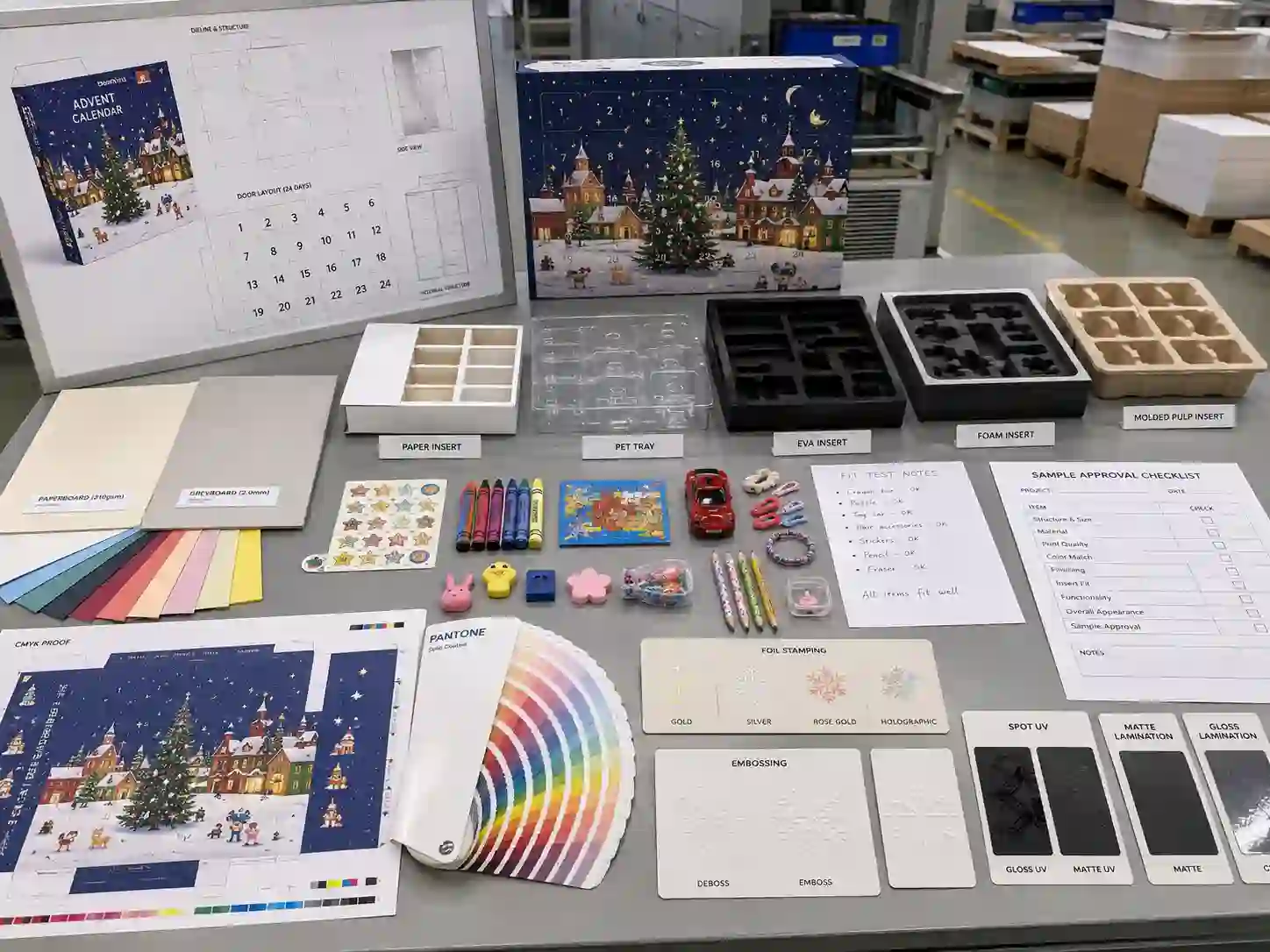 Factory planning table for kids advent calendar box dielines, inserts, material swatches, artwork proofs, and finishing samples