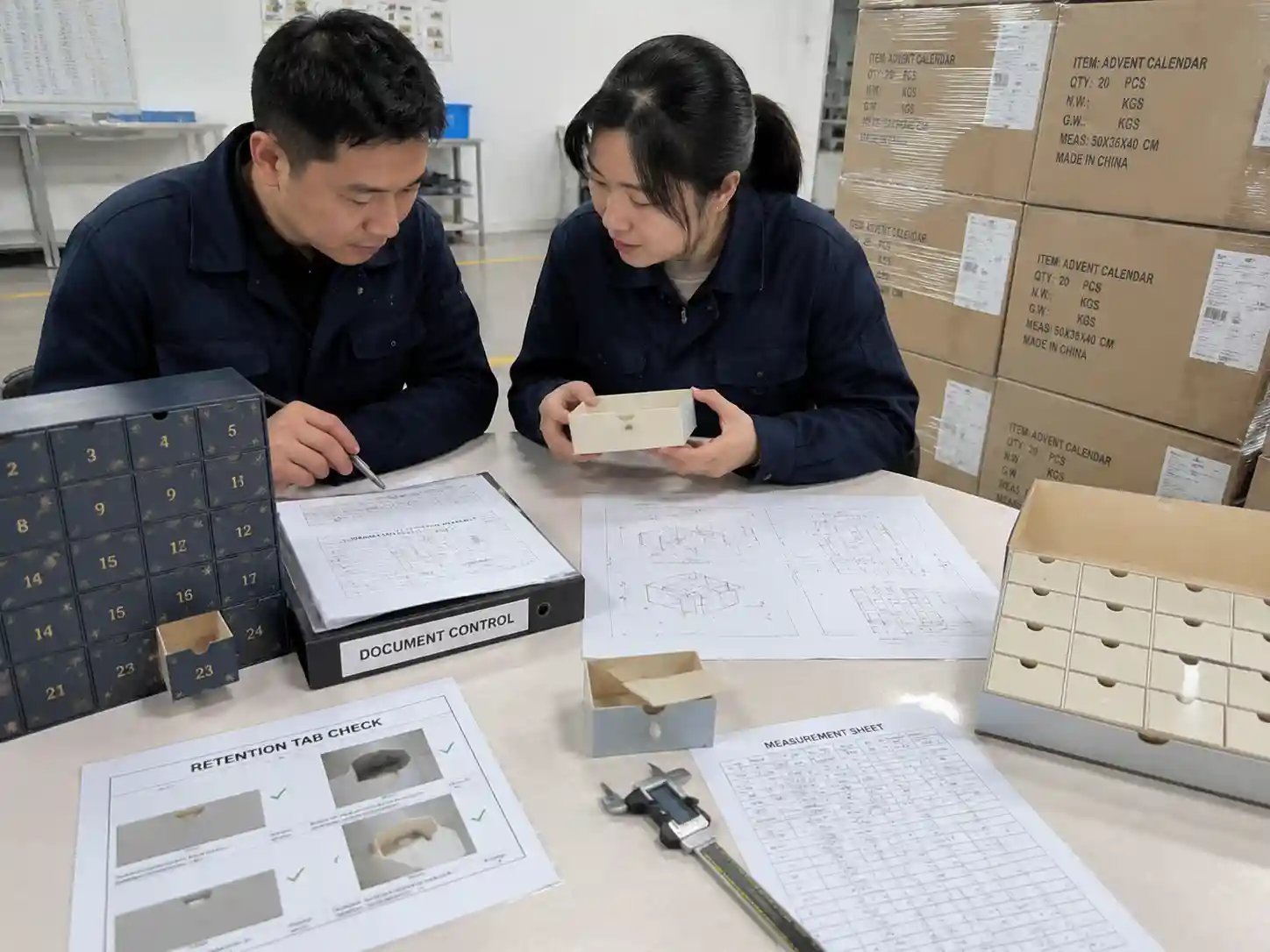 QC staff verifying drawer stop retention tab performance with inspection documents and packaging samples