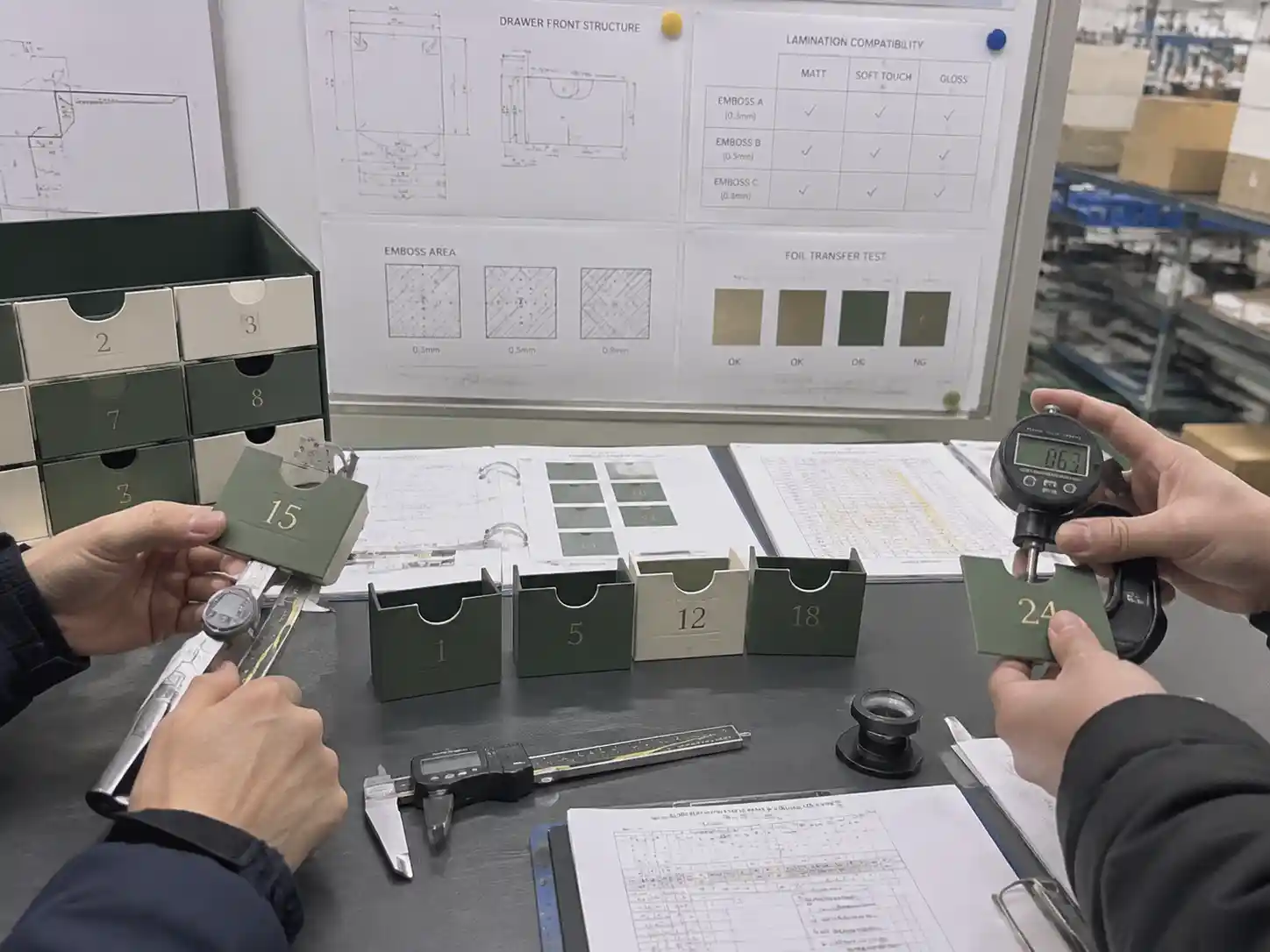 Packaging engineers measuring embossed drawer front samples during structural and finishing validation.