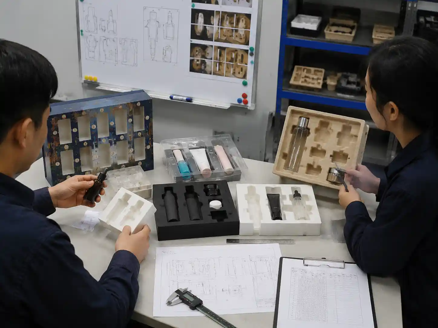 Packaging engineers reviewing fully loaded insert samples for cavity fit and retention failure checks