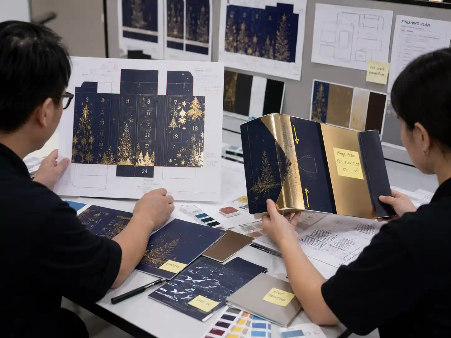 Packaging designers reviewing foil finishes and hinge artwork to prevent foil cracking across fold lines.