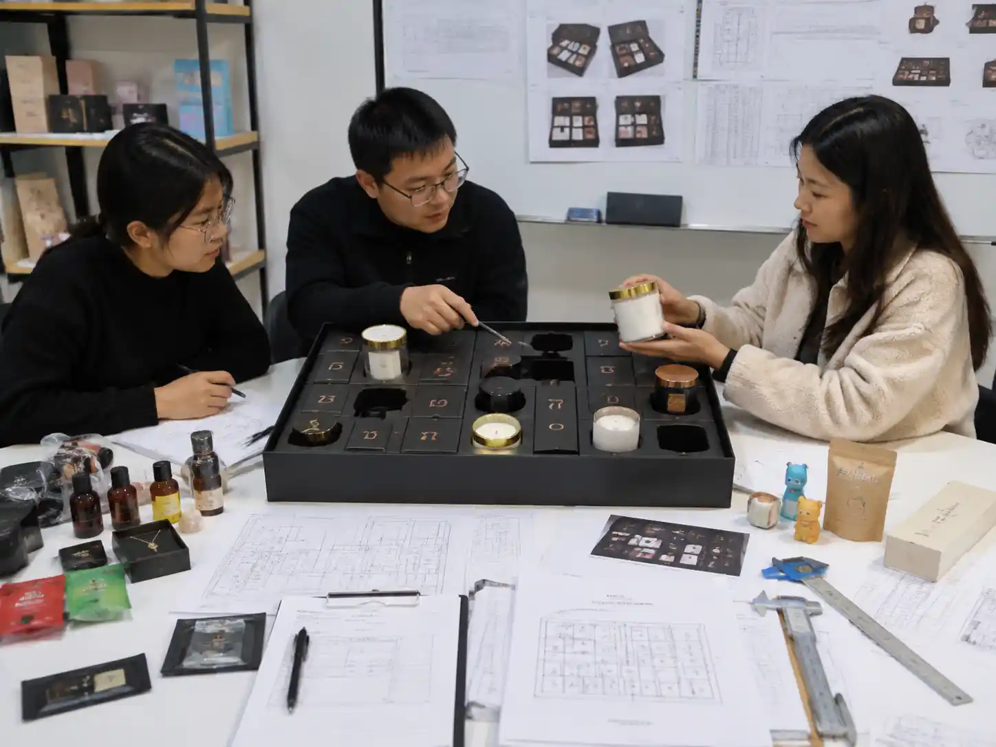 Packaging specialists reviewing candle jar inserts for lid and wax surface protection during transit
